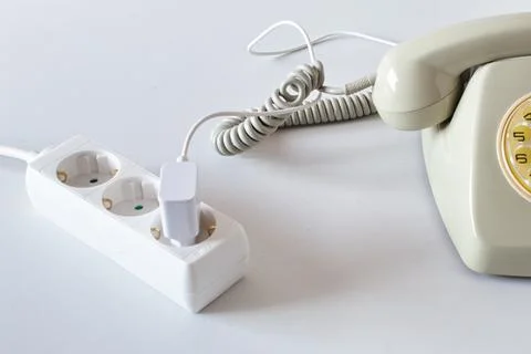 Old technology telephone connected to the electrical network through a plug Stock Photos