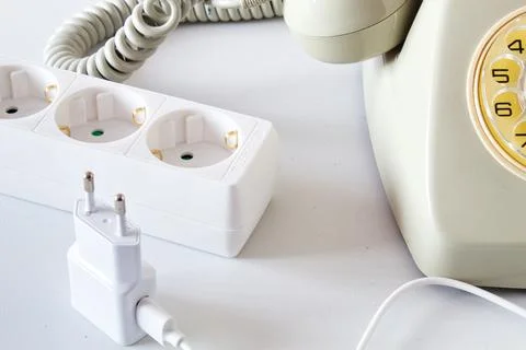 Old technology telephone connected to the electrical network through a plug Stock Photos