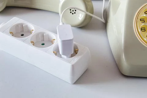 Old technology telephone connected to the electrical network through a plug Stock Photos