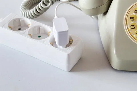Old technology telephone connected to the electrical network through a plug Stock Photos