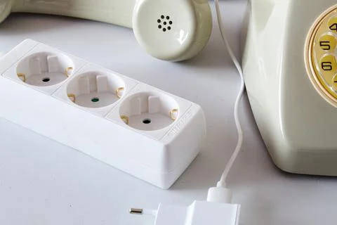 Old technology telephone connected to the electrical network through a plug Stock Photos