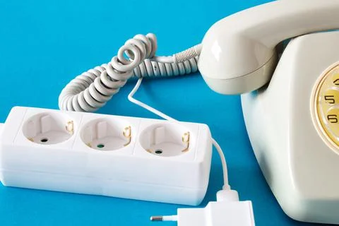 Old technology telephone connected to the electrical network through a plug Stock Photos