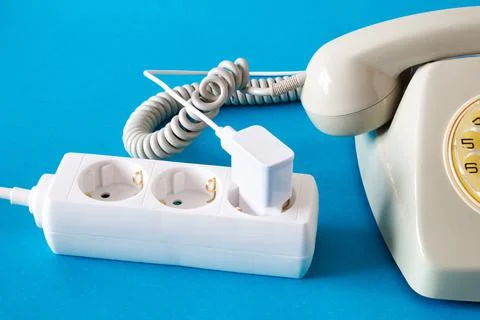 Old technology telephone connected to the electrical network through a plug Stock Photos