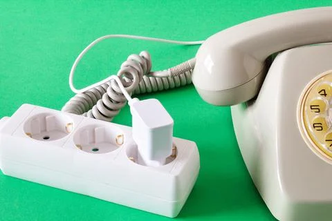 Old technology telephone connected to the electrical network through a plug Stock Photos