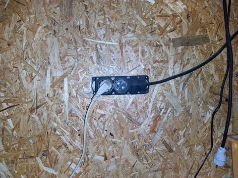 Old tee for a socket in the garage fixed to a wooden wall. Stock Photos