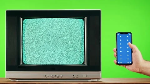 Old television with grey interference screen on green background and smartphone Stock Footage 168990016