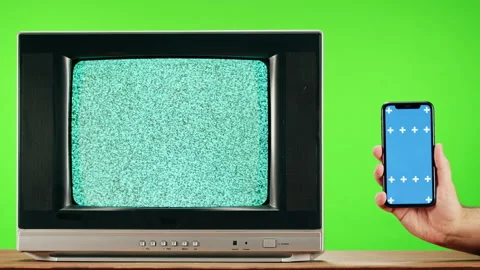Old television with grey interference screen on green background and smartphone Stock Footage 169198977