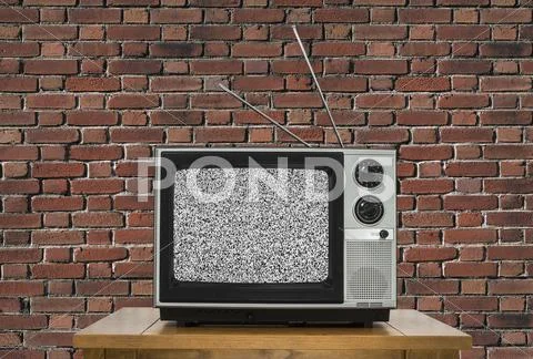 Old Television With Static Screen And Brick Wall