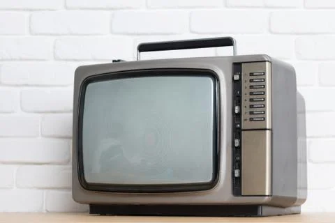 Old television on a white brick wall background. Stock Photos