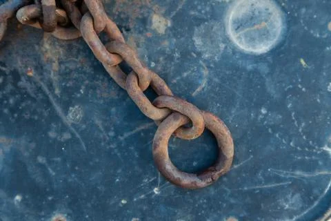An old thick iron rusty chain of brown color with a ring below on blue paint  Foto stock