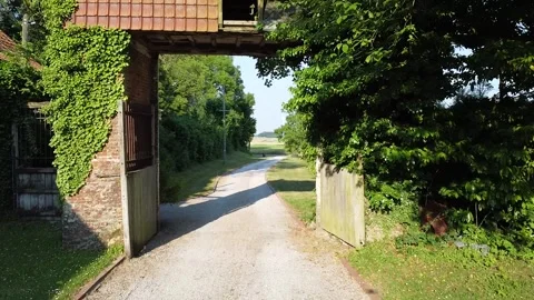 Old tiled farm buildings fly through archway windfarm drone Stock Footage 250405207
