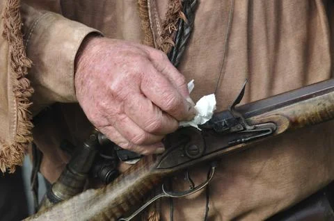 Old timer packing a paper wad into a blackpowder flintlock rifle Stockfoto's