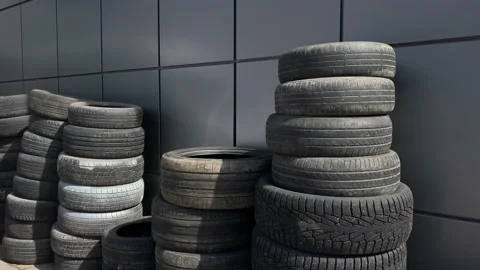 Old tires stand against a wall stacked for utilization and recycling Stock Footage 130791337