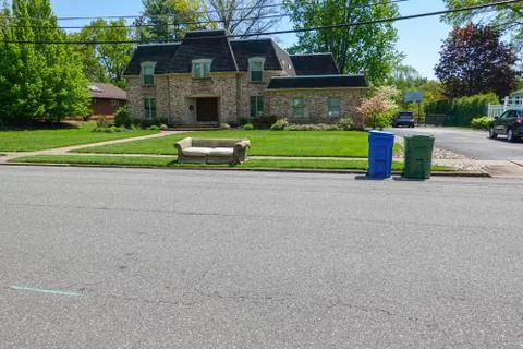An old torn couch seen on the curb in front of a big house Stock Photos