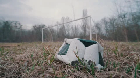 Old Torn Deflated Soccer Ball on Abandoned Field | Empty Goal Post Without Net Stock Footage 343704061