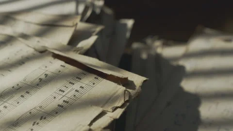 Old torn sheet music moves gently in morning sunlight and breeze, creating an Stock Footage 346800085