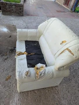 An old, torn white sofa stands on the street of Cordoba, Argentina Stock Photos