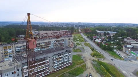 An old tower crane stands motionless near an unfinished house. Video stock 137171126