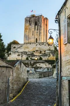 An old tower with flags on top and the road to it in the medieval town of S.. Stock Photos