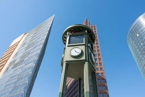 An old tower on which a clock and a traffic light are located against the Stock Photos