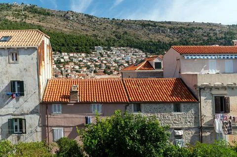 Old town structures with red roofs and greenery set against the hilly backd.. Stock Photos