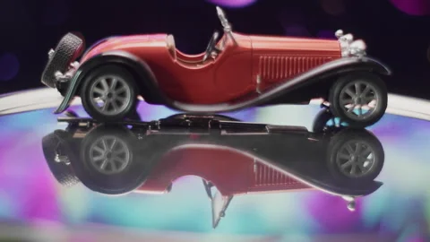Old toy red model car showcased under colorful lights at a fair Vídeos de archivo 319903187