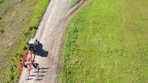 Old tractor equipped with agricultural tools running on the dirt road Stock Footage 213621837