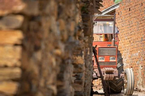 Old tractor hidden behind a stone wall Stock Photos