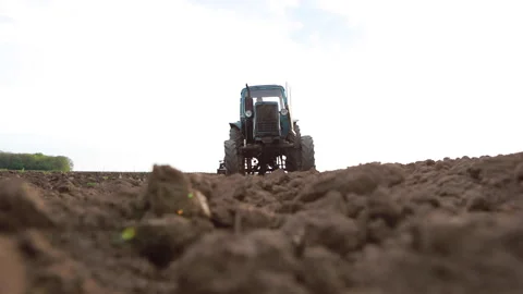 Old tractor plowing field, preparing land for sowing, driving over the camera at Stock Footage 134975486