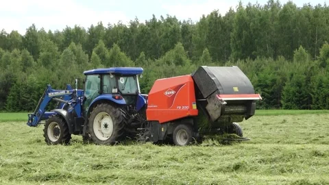 Old tractor pulls a bale wrapper across a cut grass field Video stock 337256966