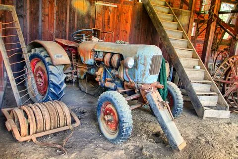 An old tractor is sitting in a barn Stock Photos