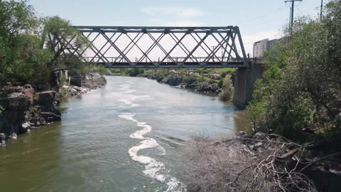 Old train bridge spans the Snake River in downtown Idaho Falls, slow motion Stock Footage 248326173