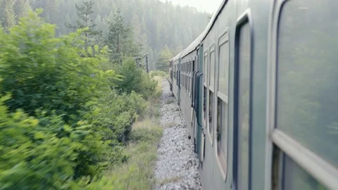 Old train moving forward on railroad track laid through forest on mountain at Stock Footage 232238394