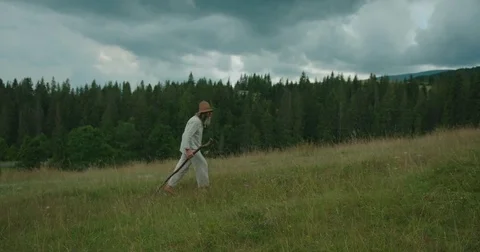 The old traveller in old clothes is walking along the beautiful green mountains Stock Footage