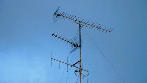 Old TV antenna array on residential rooftop against overcast sky. Analog Stock Footage 342334298