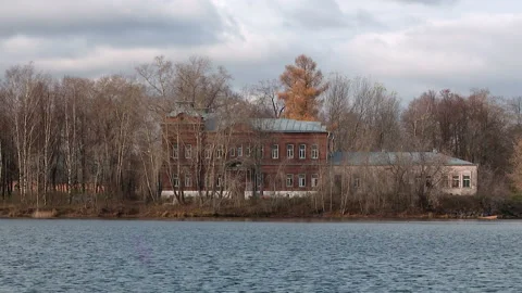Old two-storey red brick house on the shore of the pond in the fall Stock Footage 85547663