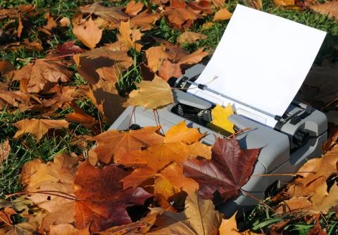 Old typewriter and fallen maple leaves Stock Photos
