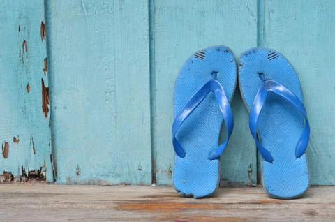 Old used blue flip-flops on wooden wall 库存照片