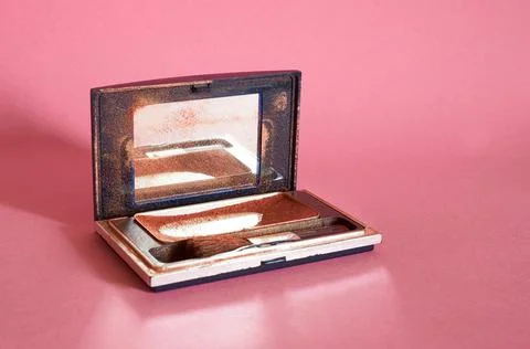 Old used brown eye shadow and a brush in a dirty case with a mirror Stock Photos