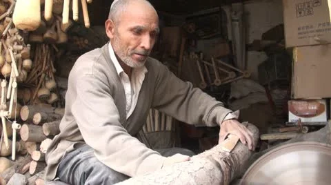 Old Uyghur man cuts large chunks of wood Stock Footage