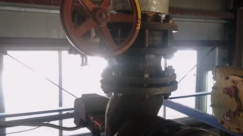An old valve with a yellow round steering wheel on a heating pipe in a boiler Stock Footage 219422692