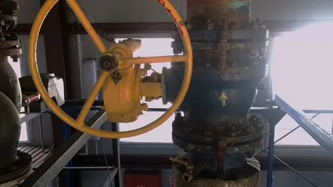 An old valve with a yellow round steering wheel on a heating pipe in a boiler Stock Footage 219644035