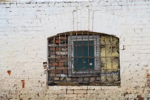 Old vaulted window with brick wall with metal grate and wooden frame, white p Stock Photos