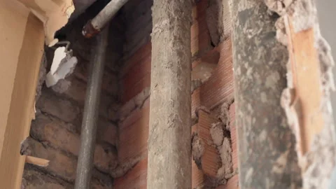 Old vertical rusty pipes passing along the brick wall on construction site Video stock 135350234