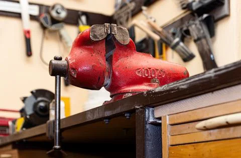 Old vice clamp in the workshop. Red rusty vise on the table. Stock Photos