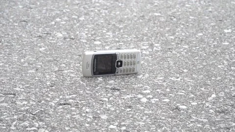 An old vintage candybar phone falling onto the ground in slow motion Stock Footage 154549632