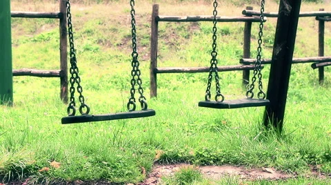 Old vintage empty swings with chains swaying at playground for child Видео 56770743