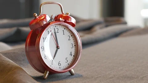 "Old vintage red alarm clock standing on a bed sheet. Bells ring on time. 4KHD" Stock Footage