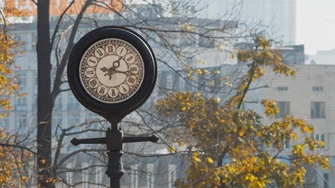 The old vintage round clock with black frame on the street in the autumn park Stock Footage 119760467