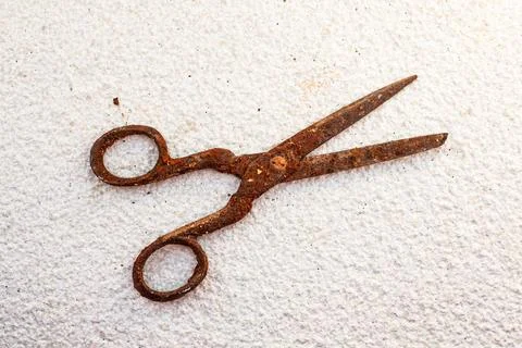 Old vintage scissors covered in rust on white stone background - isolated Stock Photos